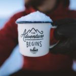 Girl holding coffee mug saying "The Adventure Begins"