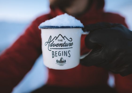 Girl holding coffee mug saying "The Adventure Begins"