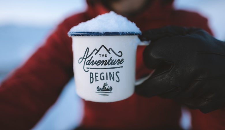 Girl holding coffee mug saying "The Adventure Begins"